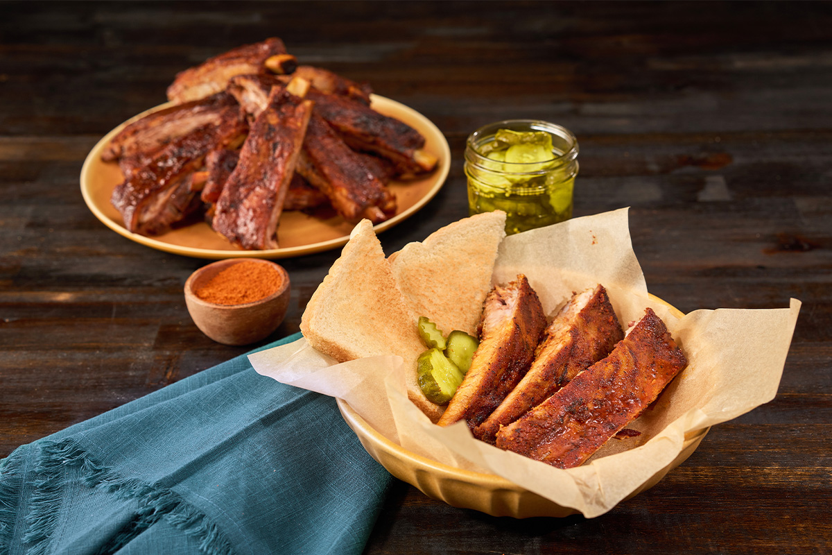 Nashville hot-style pork spareribs served with pickle chips and bread slices | Prairie Fresh®