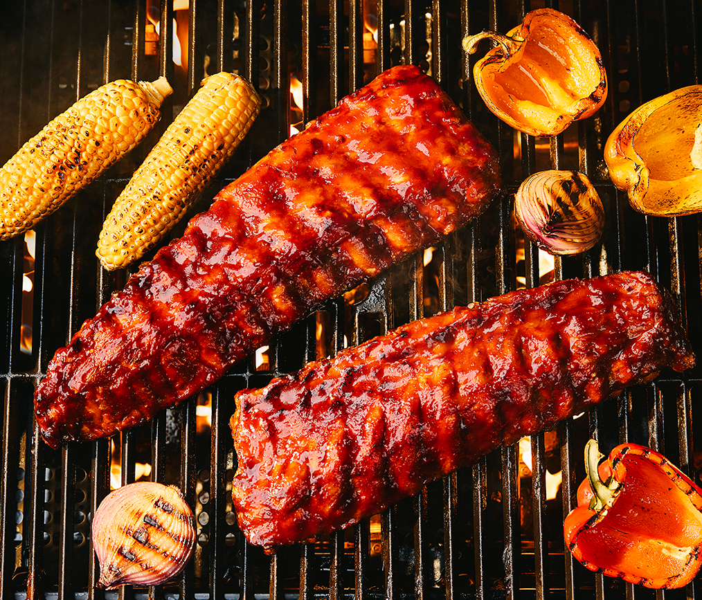 Grilled pork backribs brushed with tangy barbecue sauce and grilled corn, onions and peppers | Prairie Fresh®